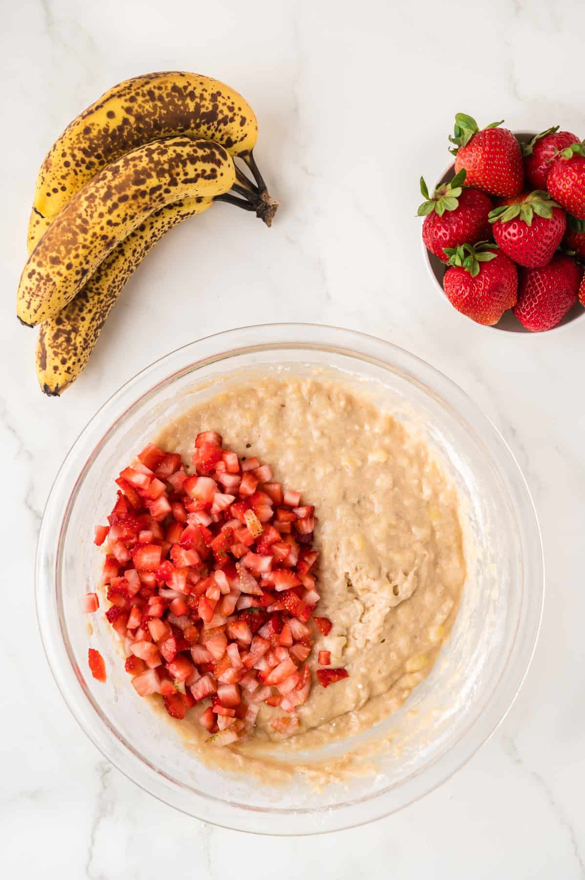 Adding diced strawberries to banana bread batter.