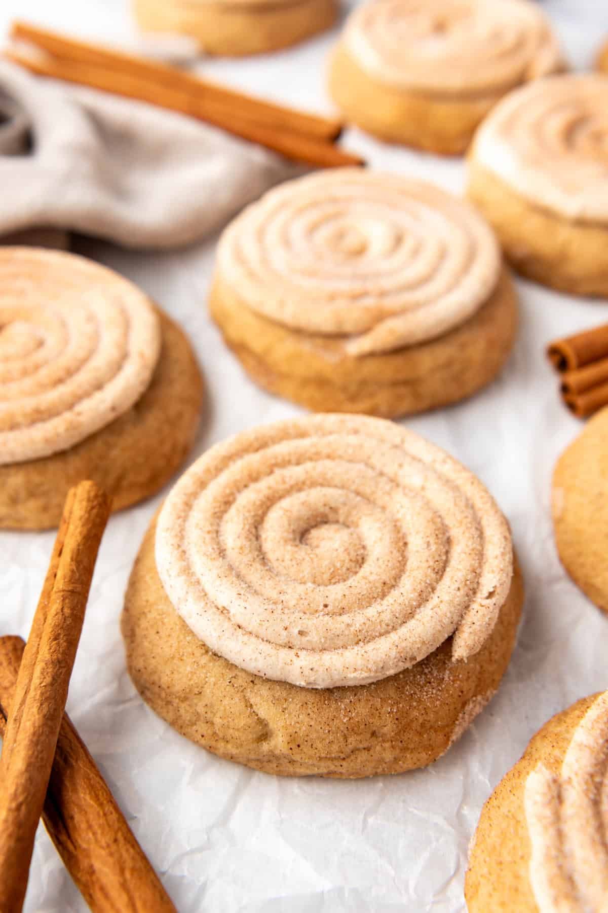 An image of frosted churro cookies surrounded by cinnamon sticks.