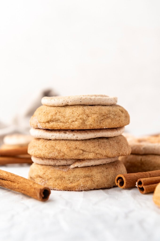 A stack of frosted churro cookies with cinnamon sticks nearby.