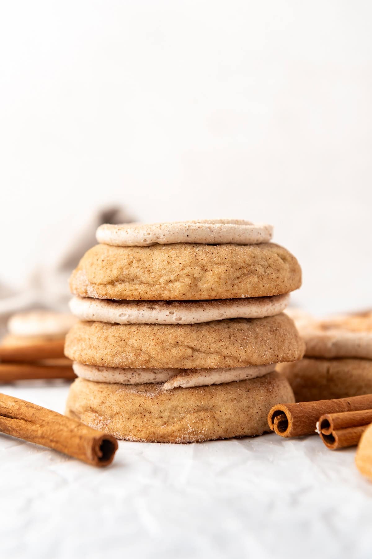 A stack of frosted churro cookies with cinnamon sticks nearby.