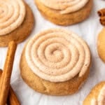 An image of frosted churro cookies surrounded by cinnamon sticks.