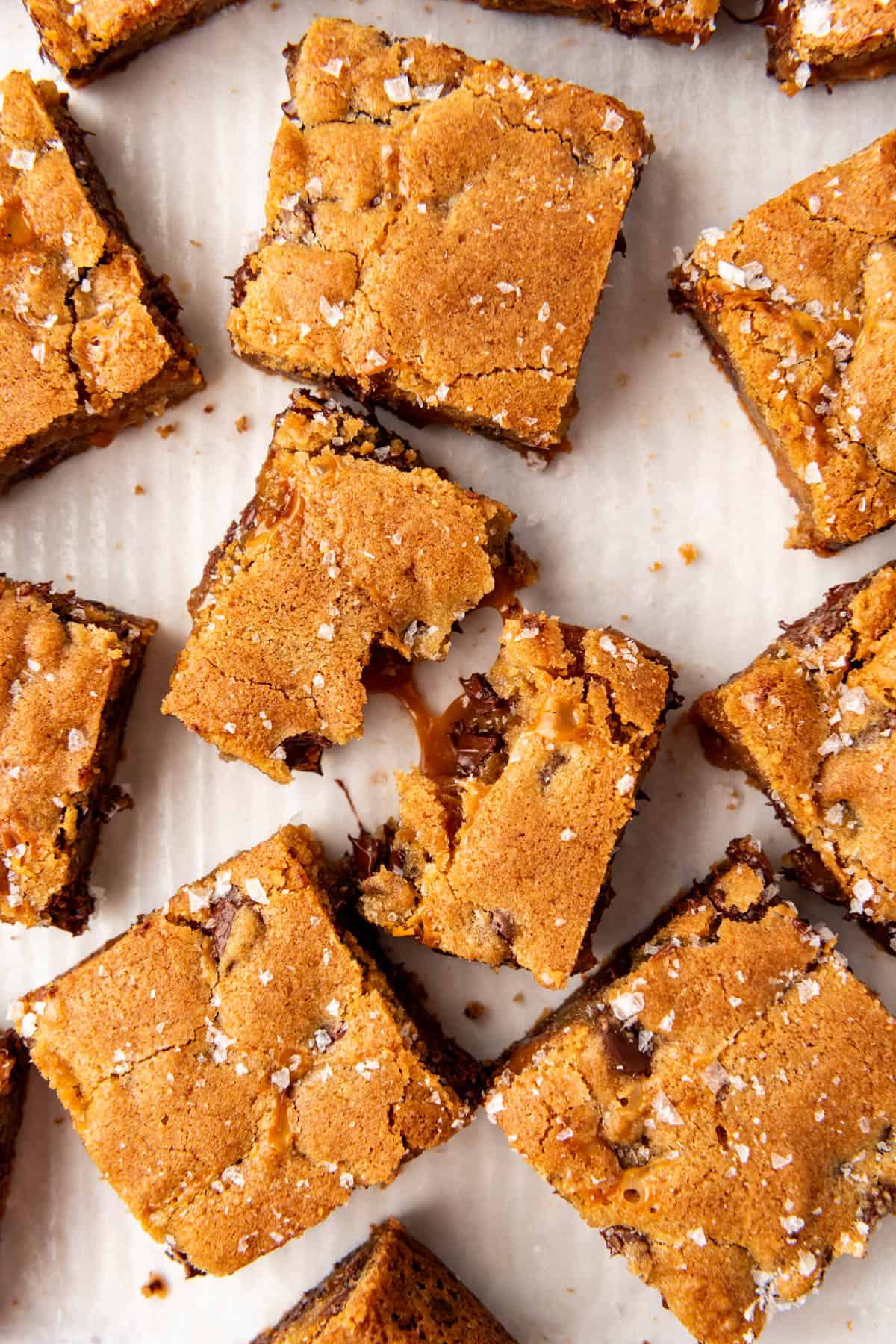 An overhead image of chocolate chip caramel bars with one bar being pulled in half in the center.