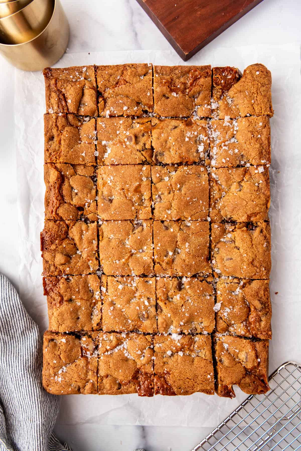 Baked chocolate chip caramel bars that have been cut into squares with flaky salt sprinkled on top.