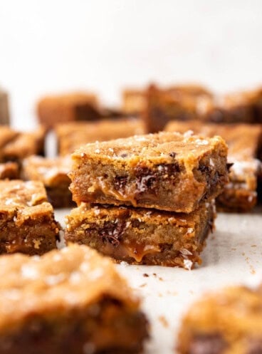 Two chocolate chip caramel bars stacked on top of each other.