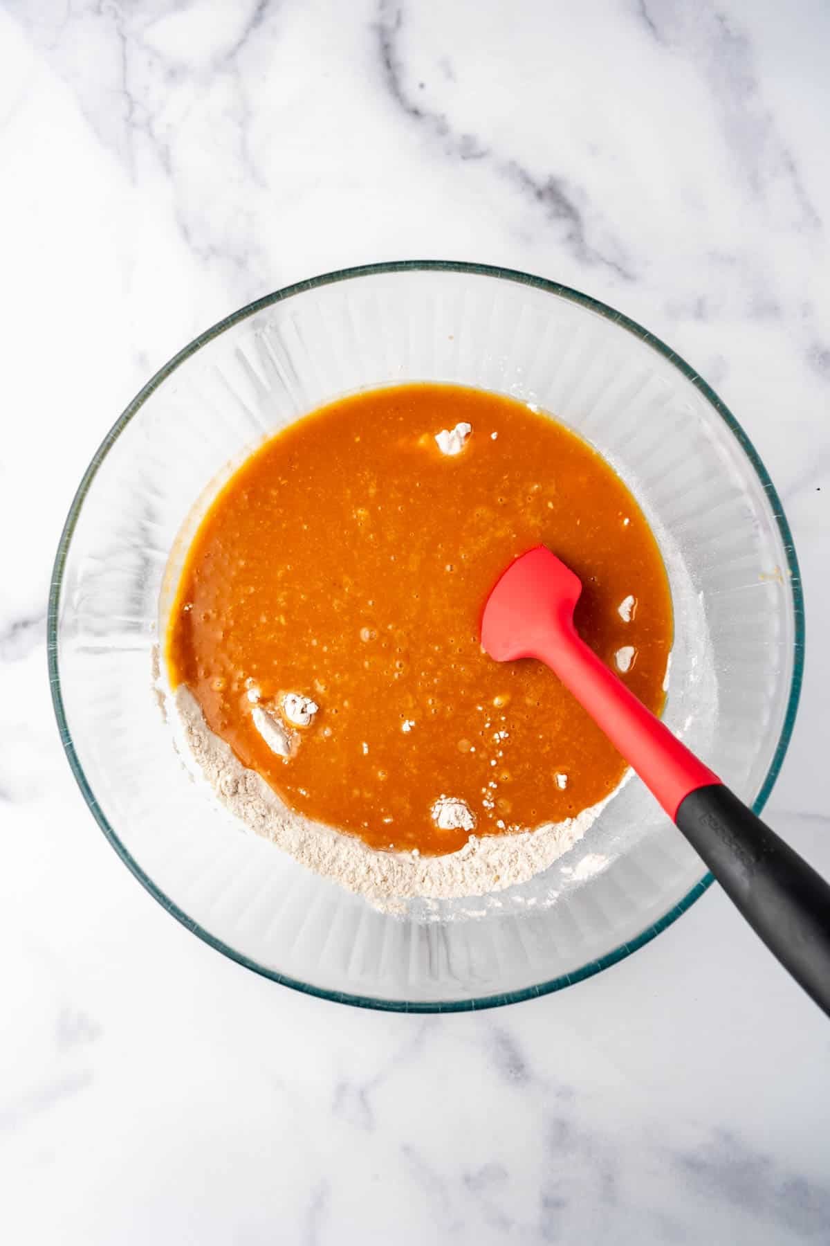 Adding wet ingredients to dry ingredients in a mixing bowl.