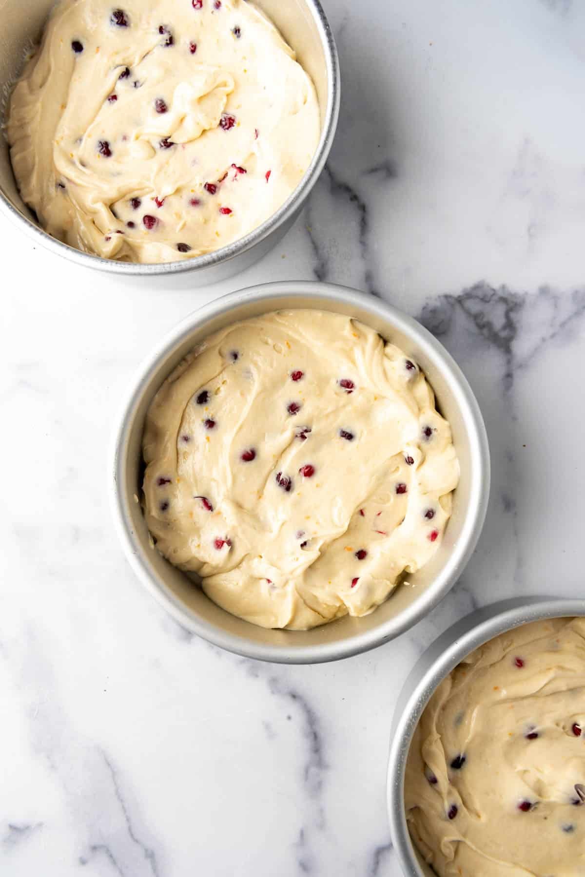 Cranberry orange cake batter in 8-inch cake pans.