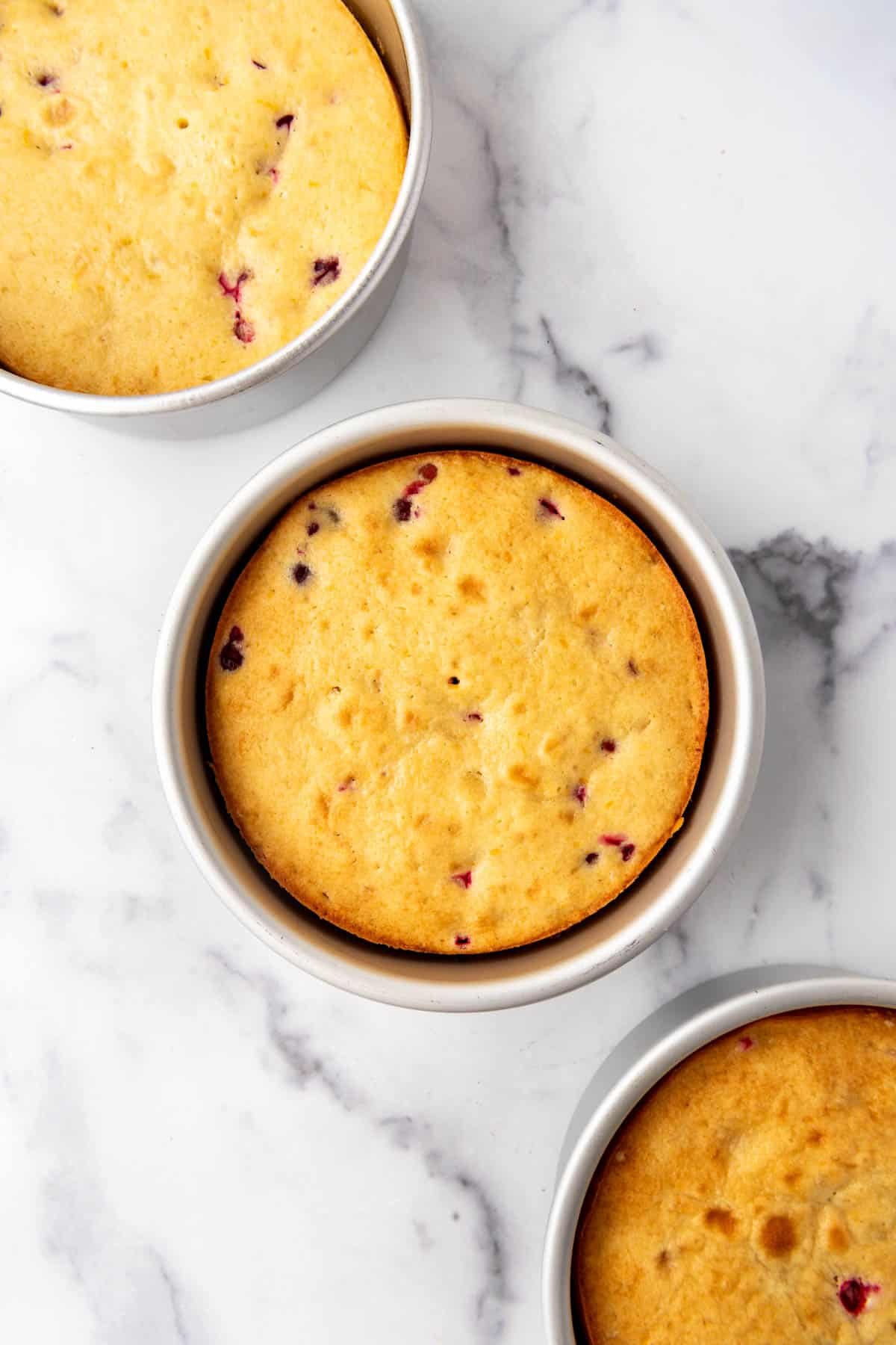 Baked cranberry orange cake layers in 8-inch pans.