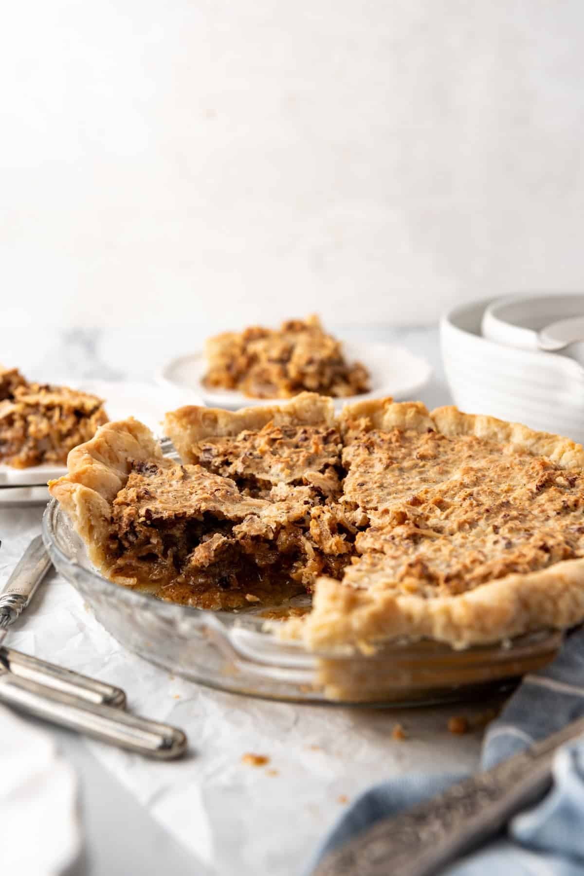 An image of a partially sliced sawdust pie with bowls and silverware around it.