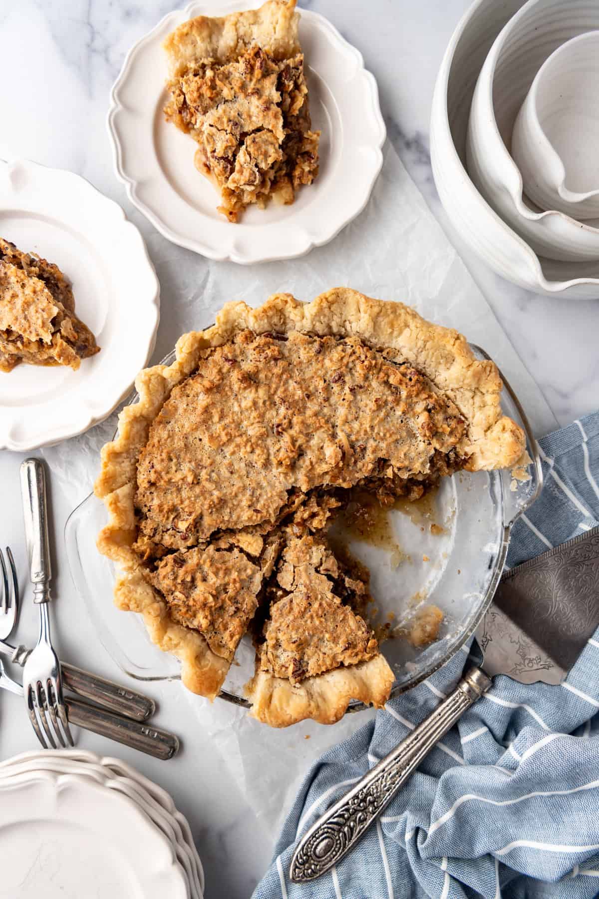 An overhead image of a sliced sawdust pie with some slices of pie on nearby plates.