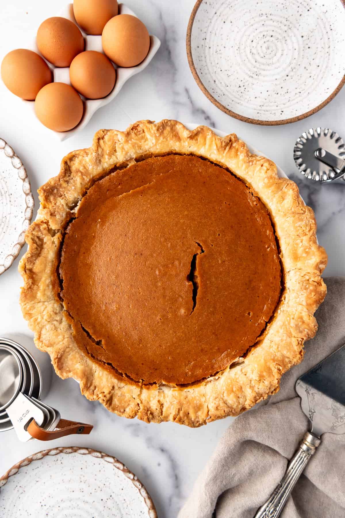 An overhead image of a sweet potato pie with a crack in the middle.