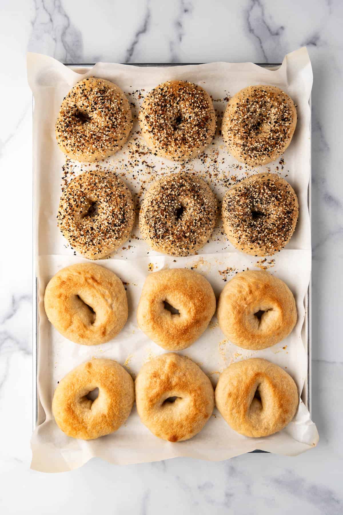 An image of a dozen baked bagels on a baking sheet.