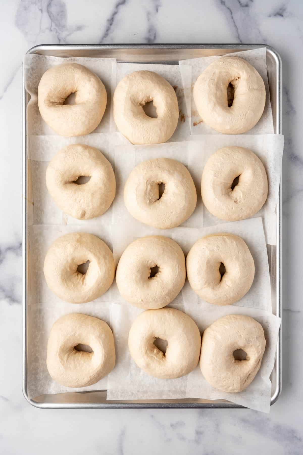 An image of puffy bagels that have been shaped and are ready to be boiled and baked.
