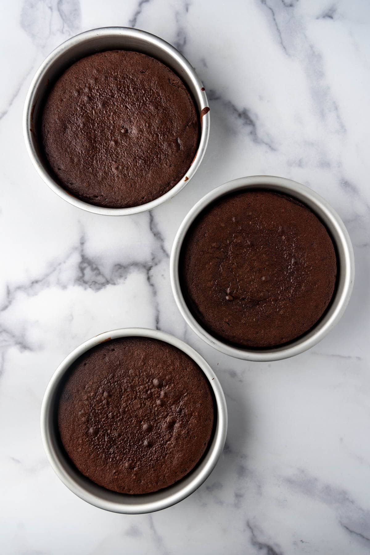 Three cake pans with baked chocolate cake.