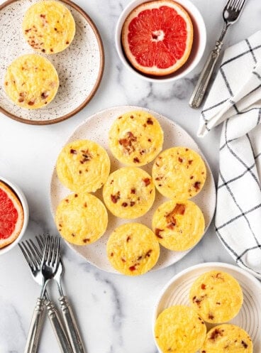 An overhead image of copycat starbucks egg bites o n a plate with grapefruit halves around it.