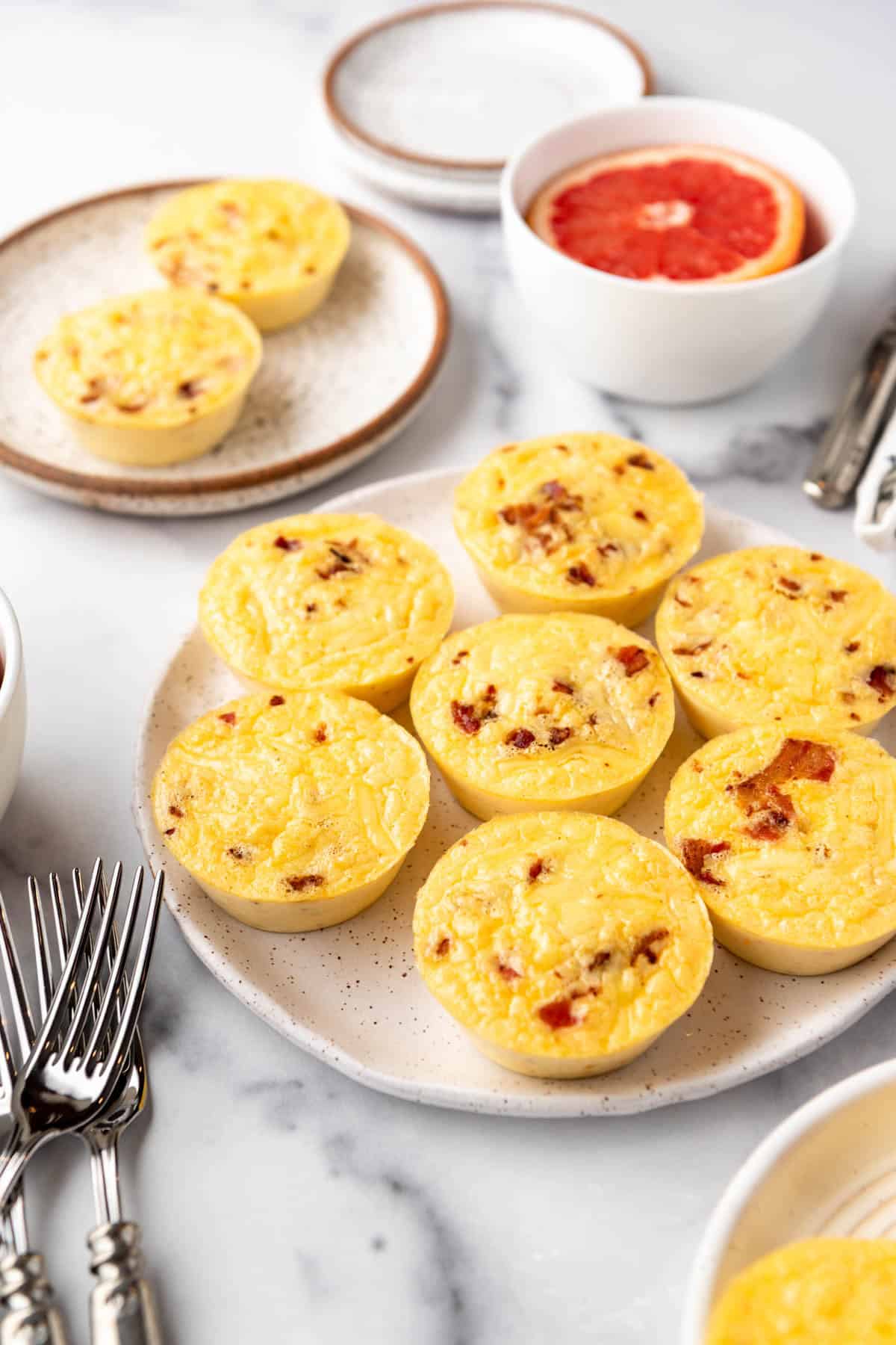 A platter of homemade egg bites in front of a bowl of grapefruit.