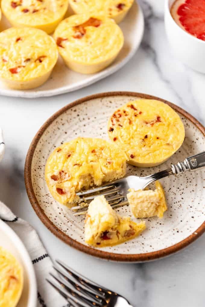 Two bacon cheese egg bites on a plate with a fork.