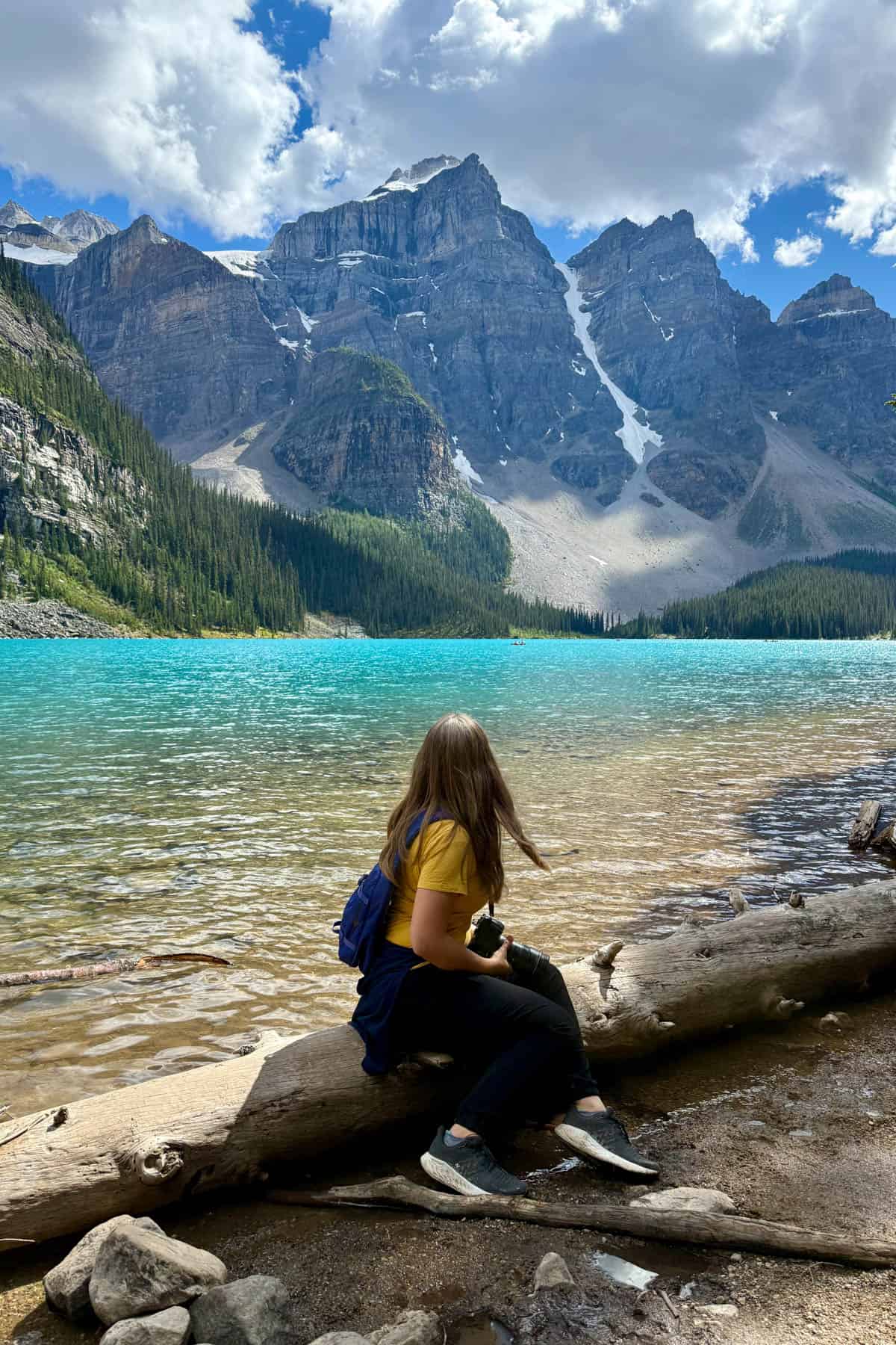 A woman sitting on a log at Moraine Lake in Banff National Park.