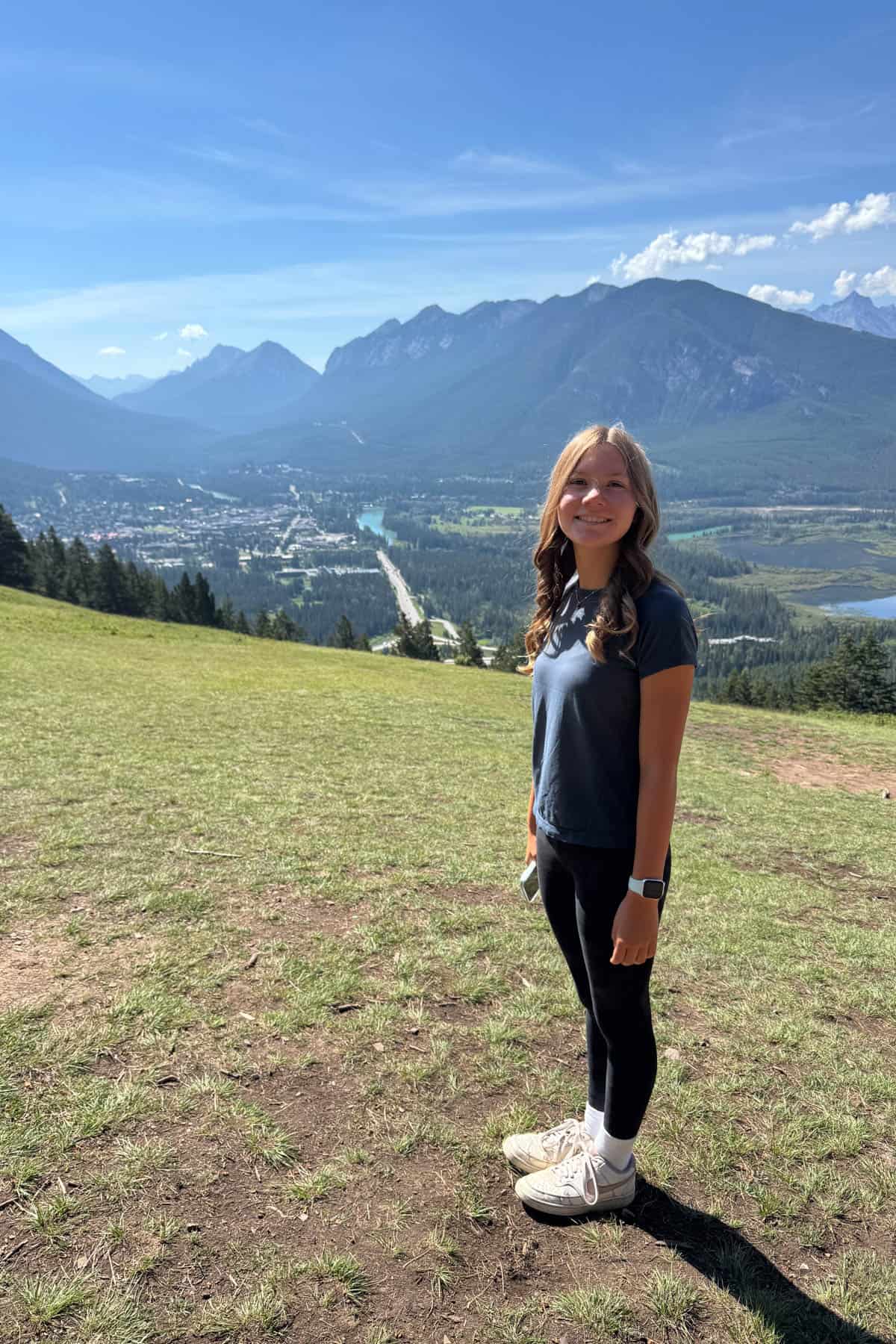 A girl standing on a mountainside with the town of Banff in the distance.