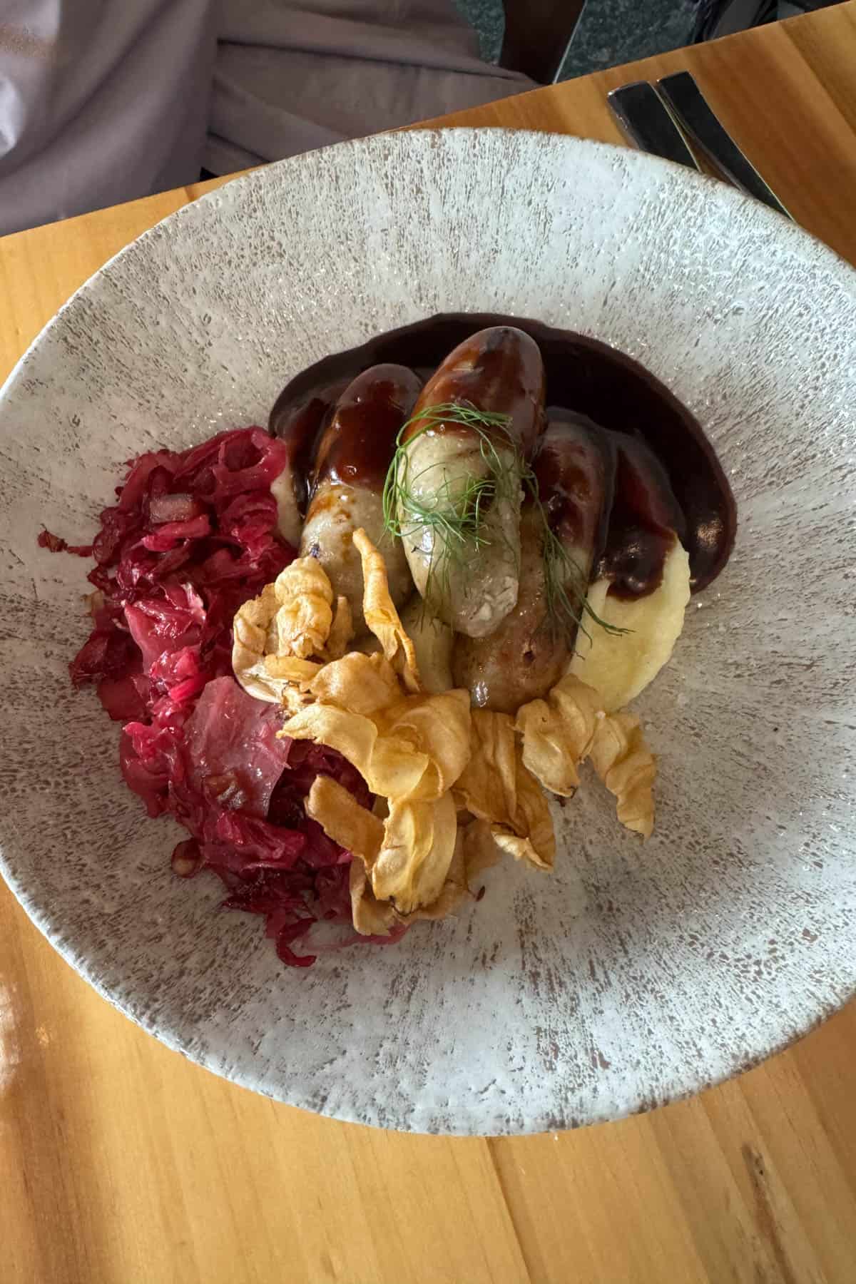 A plate of bangers and mash at a restaurant.