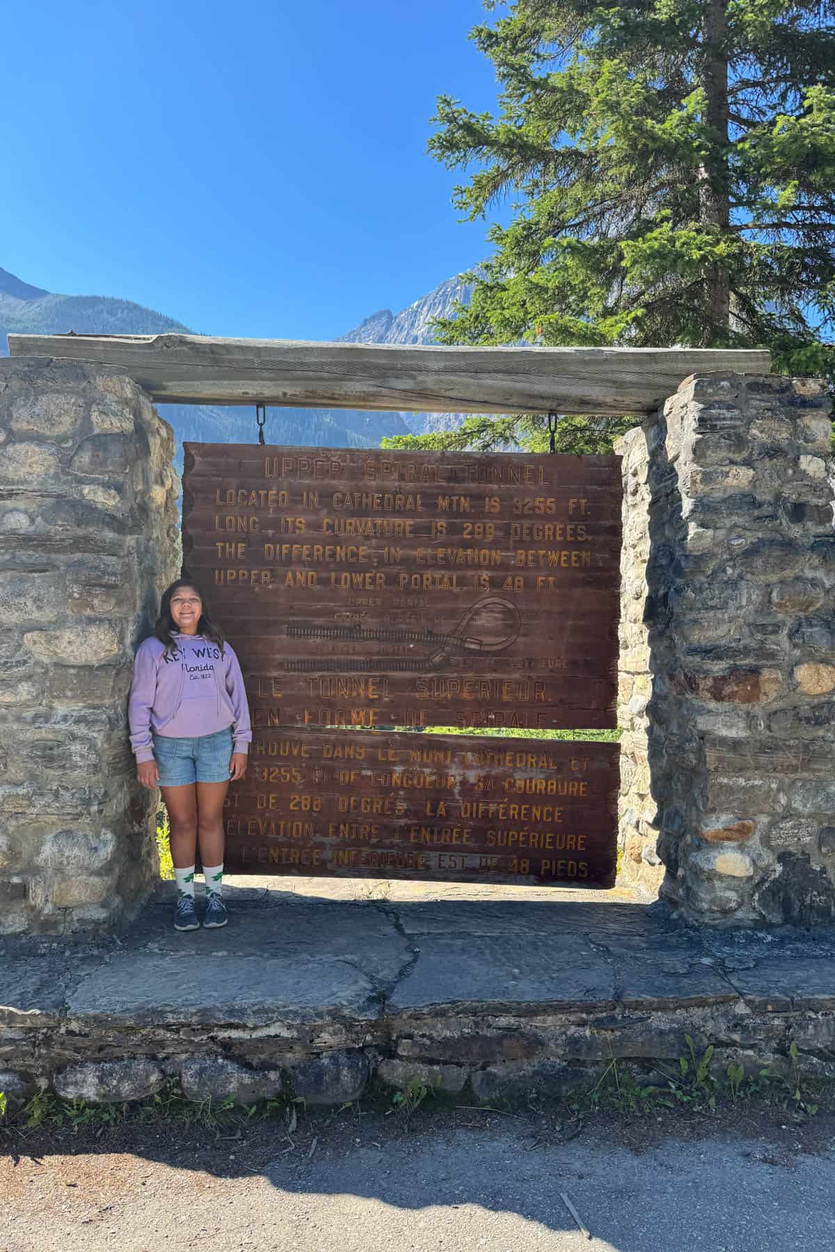 A child standing in front of the Spiral Tunnels sign in Canada.