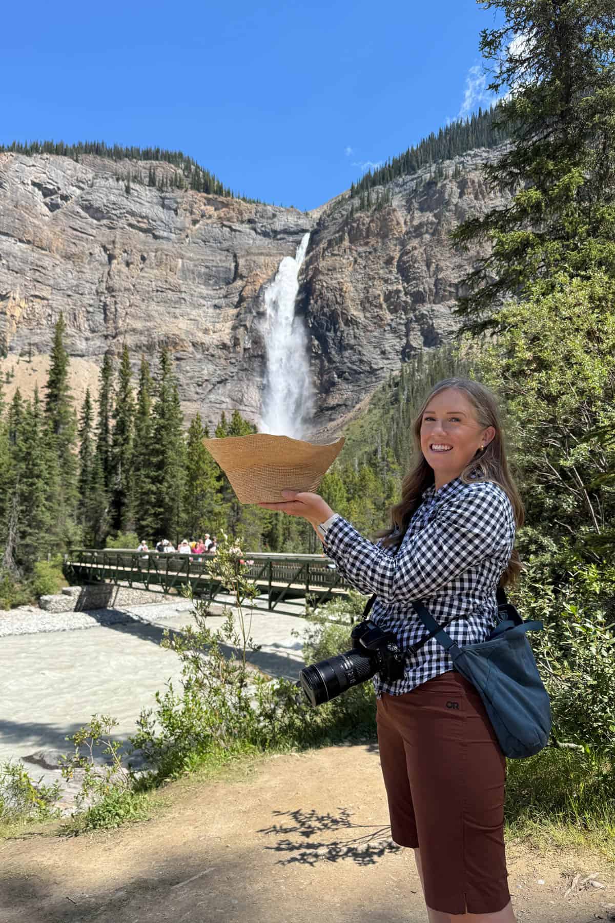 An optical illusion of a woman "catching" a waterfall in her hat.