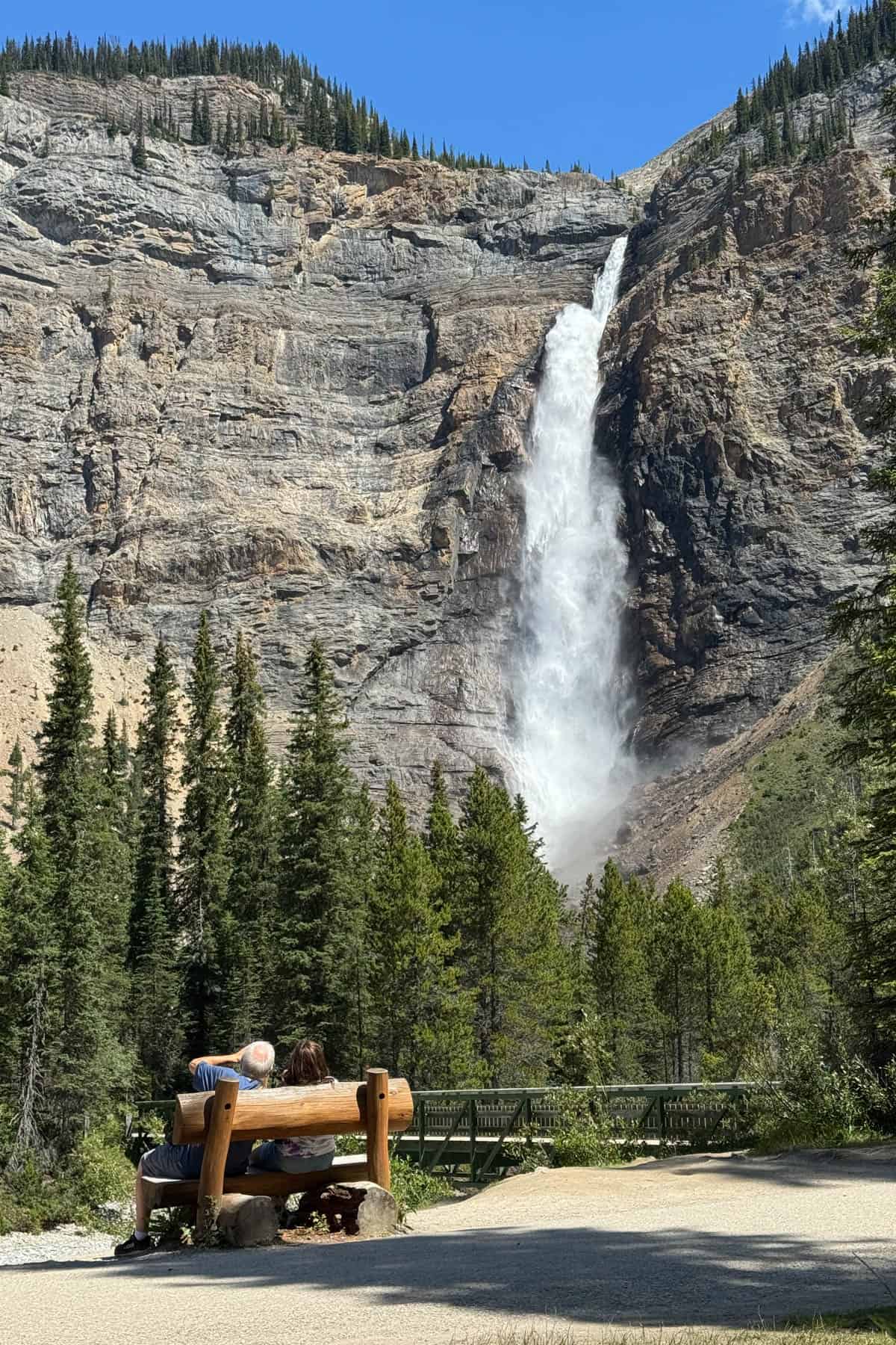 Two people on a bench in front of a waterfall.