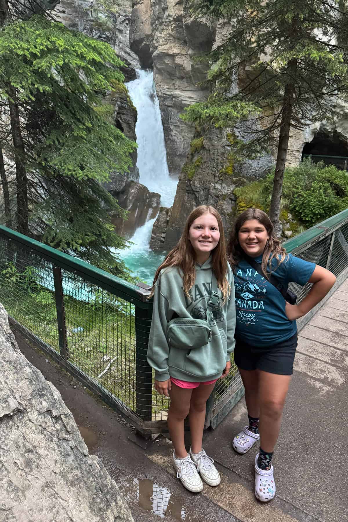 Two girls in front of a waterfall.