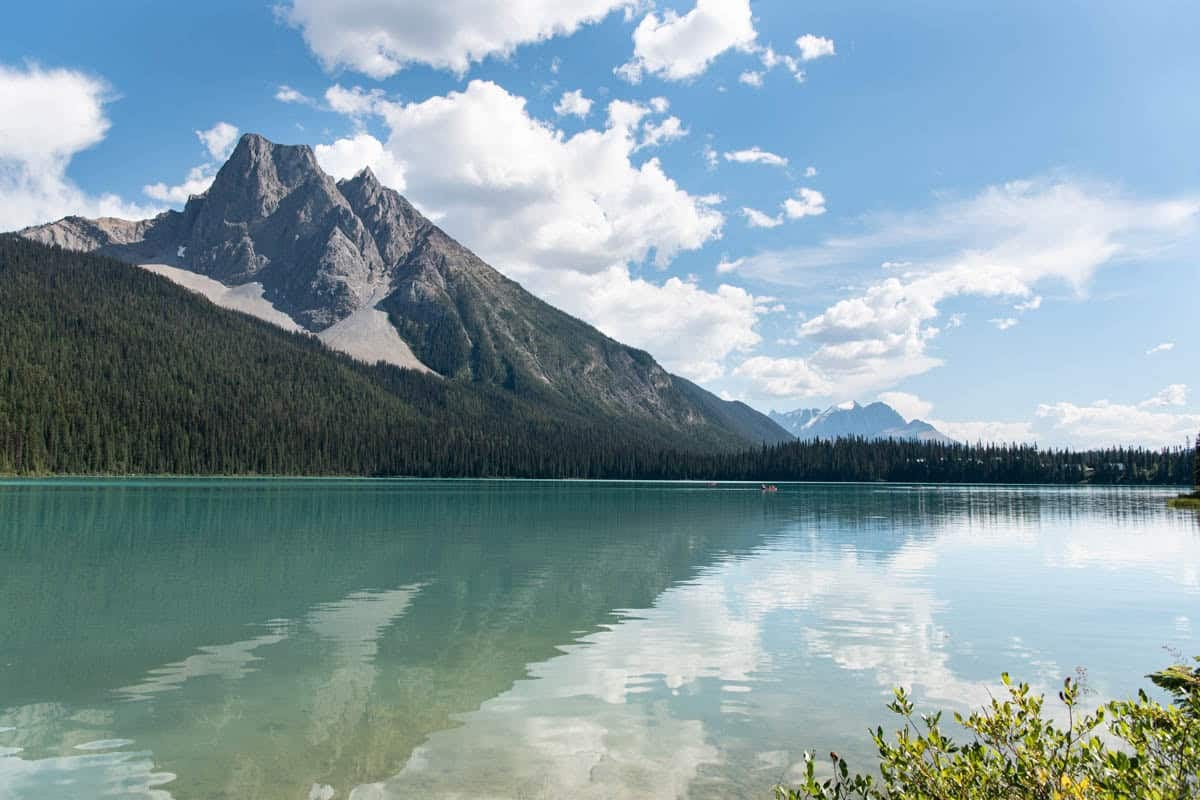 An image of a bright turquoise lake with a mountain peak reflecting off the lake surface.