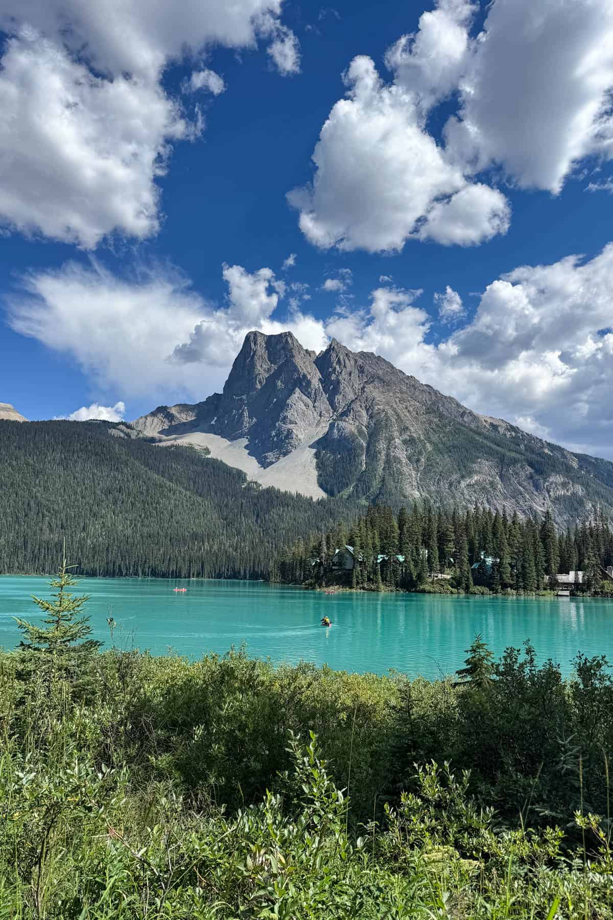 An image of a bright turquoise lake with a mountain peak behind it.