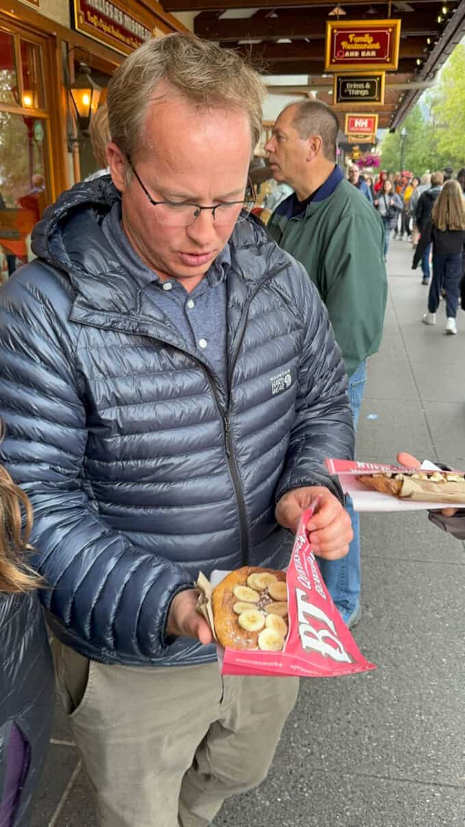 A man holding a beaver tail pastry with nutella and bananas.