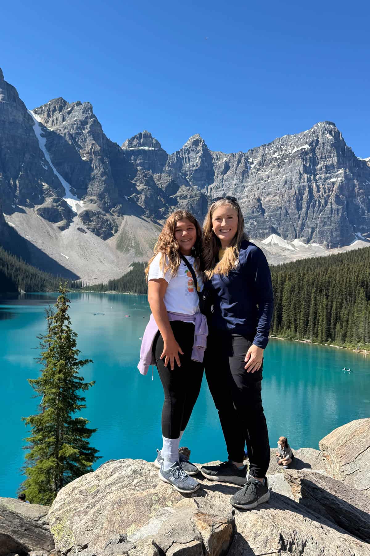 A mom and daughter standing in front of Moraine Lake in Banff National Park.
