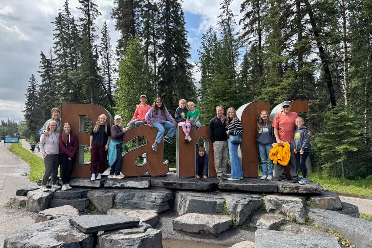 An image of a large extended family at the Banff sign in Banff, Canada.