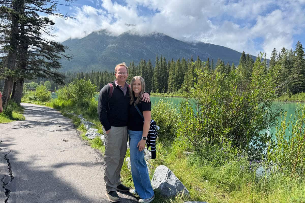 A couple standing in front of the Bow River in Banff.