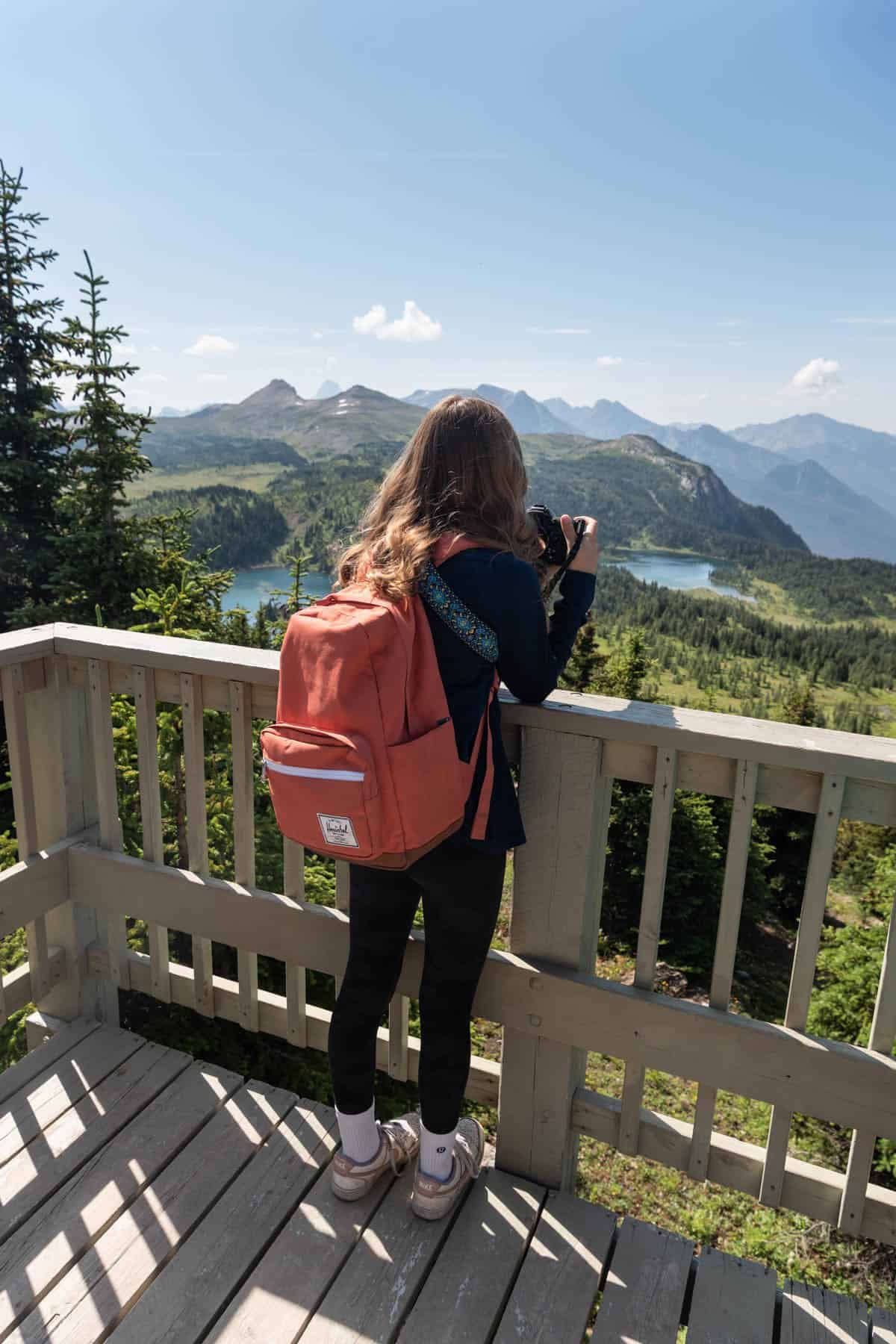 A girl taking a photo of mountains.