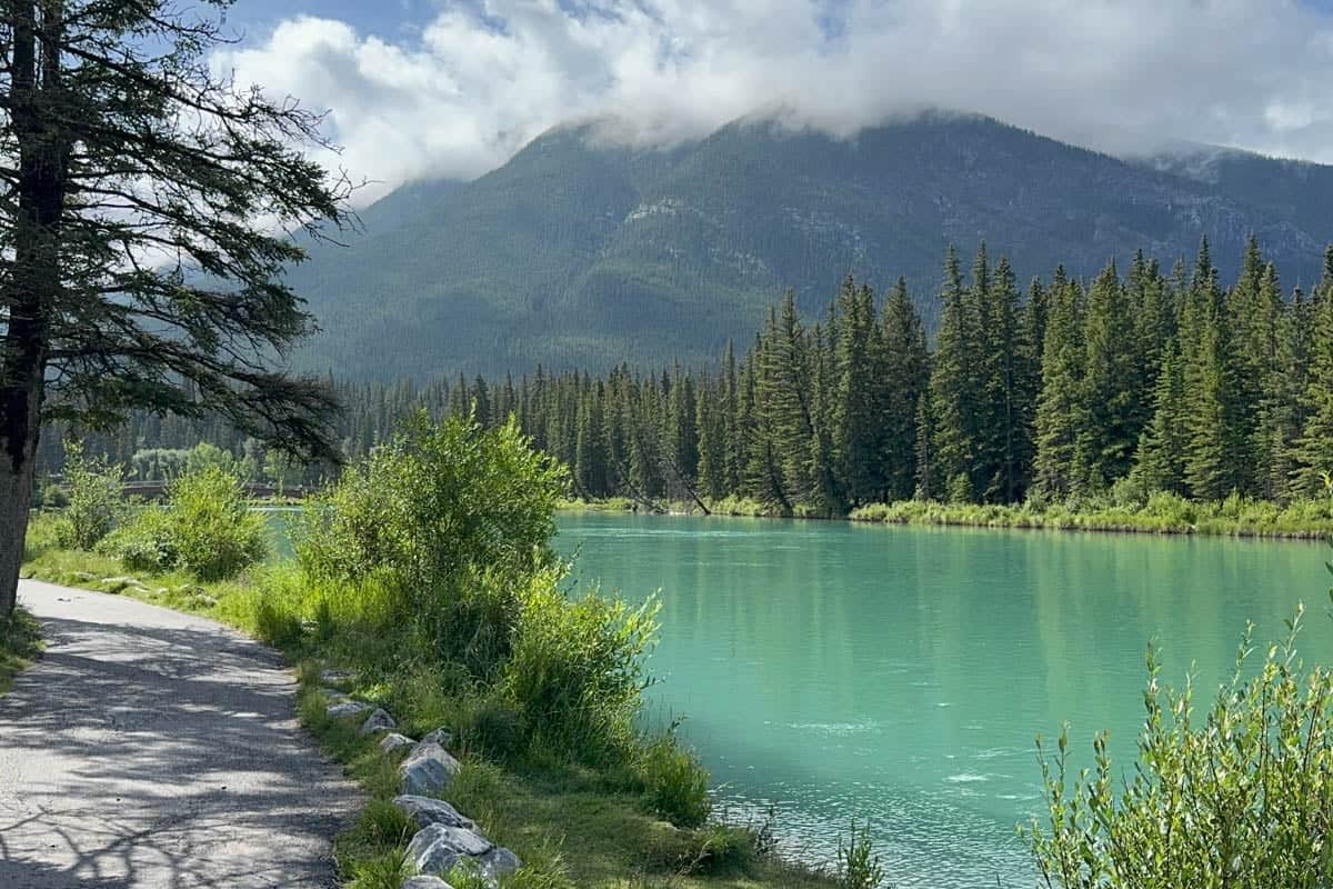An image of the Bow River in Banff with clouds, mountains, and trees in the background.