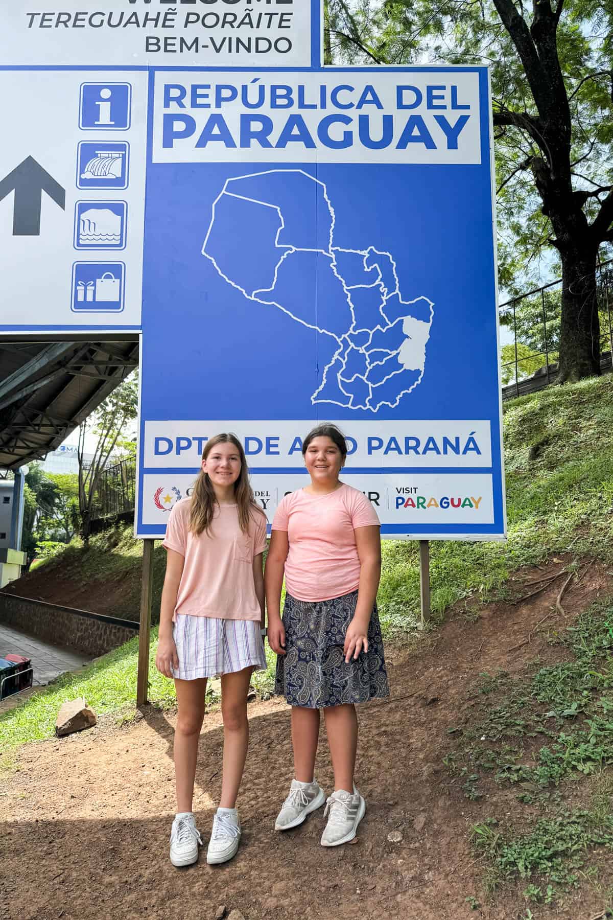 Two girls in front of the sign for Paraguay.