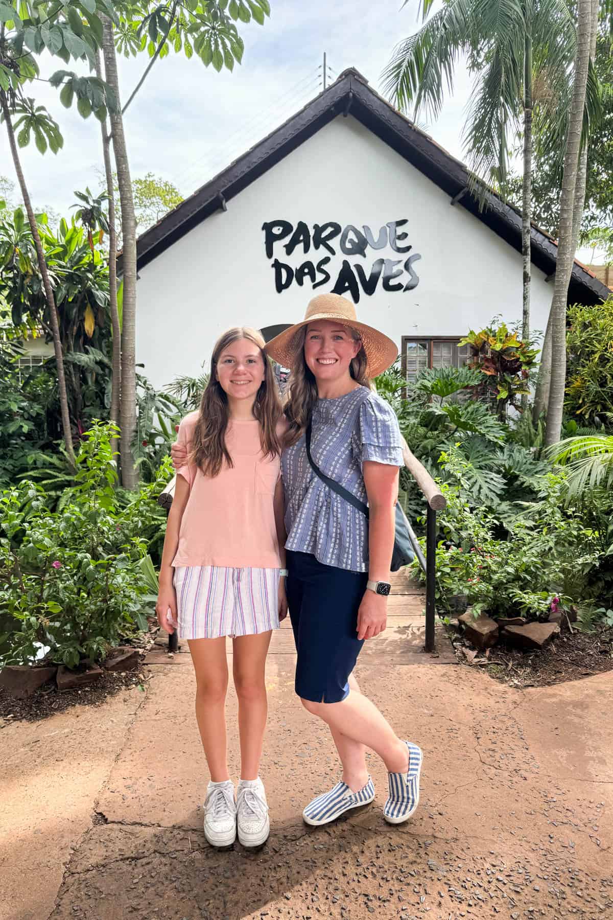 A mother and daughter in front of the entrance sign for Parque das Aves in Brazil just outside of Iguassu Falls.