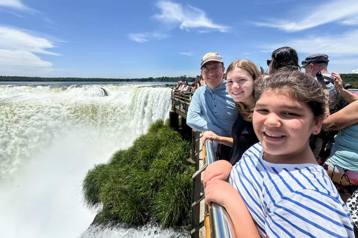 A family at a railing with Iguazu Falls behind them.