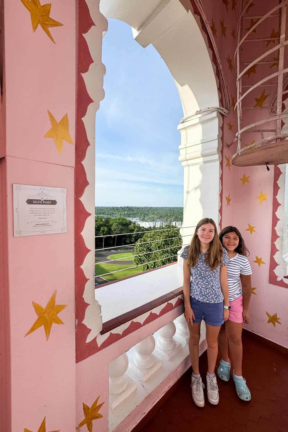 An image of two girls in the lookout tower at Hotel das Cataras with Iguazu Falls behind them in the distance.