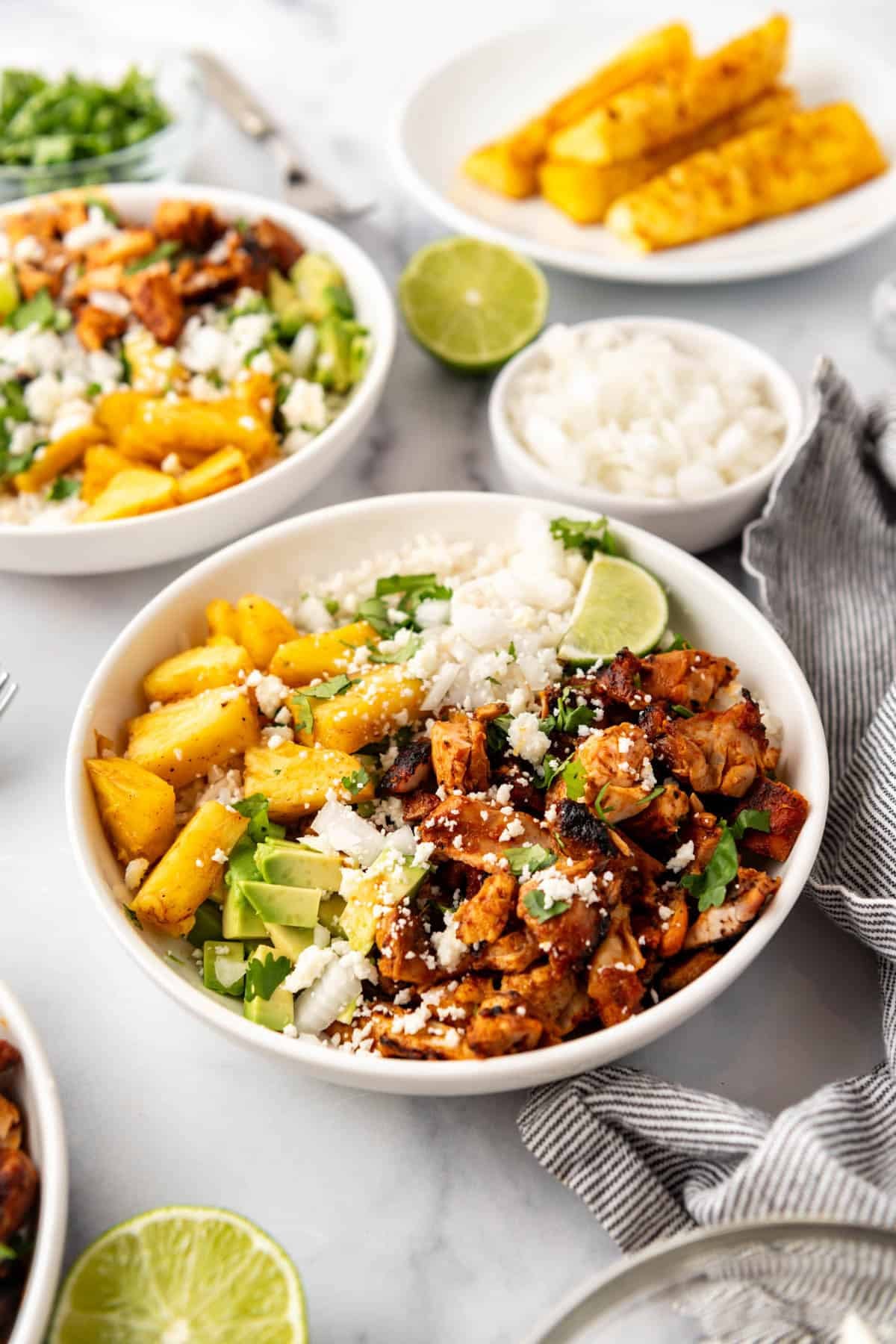 An image of chicken al pastor bowls with chopped chicken, rice, diced avocado, and diced pineapple.