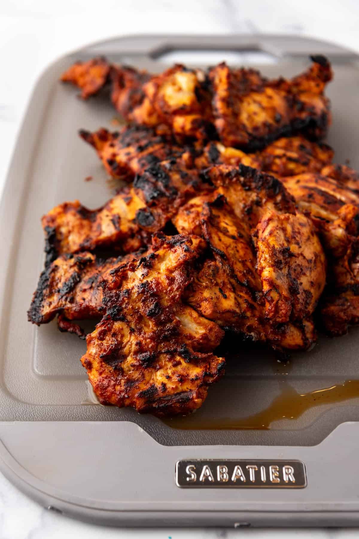 Grilled chicken thighs on a cutting board.