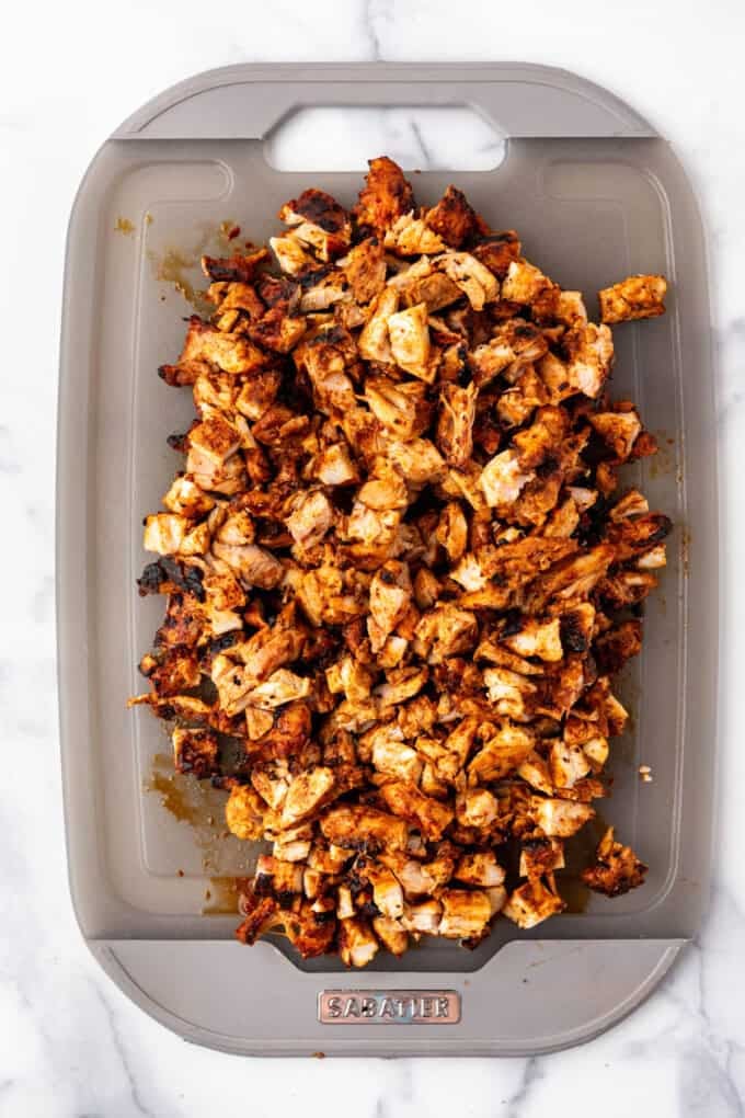 An overhead image of chopped chicken al pastor on a cutting board.