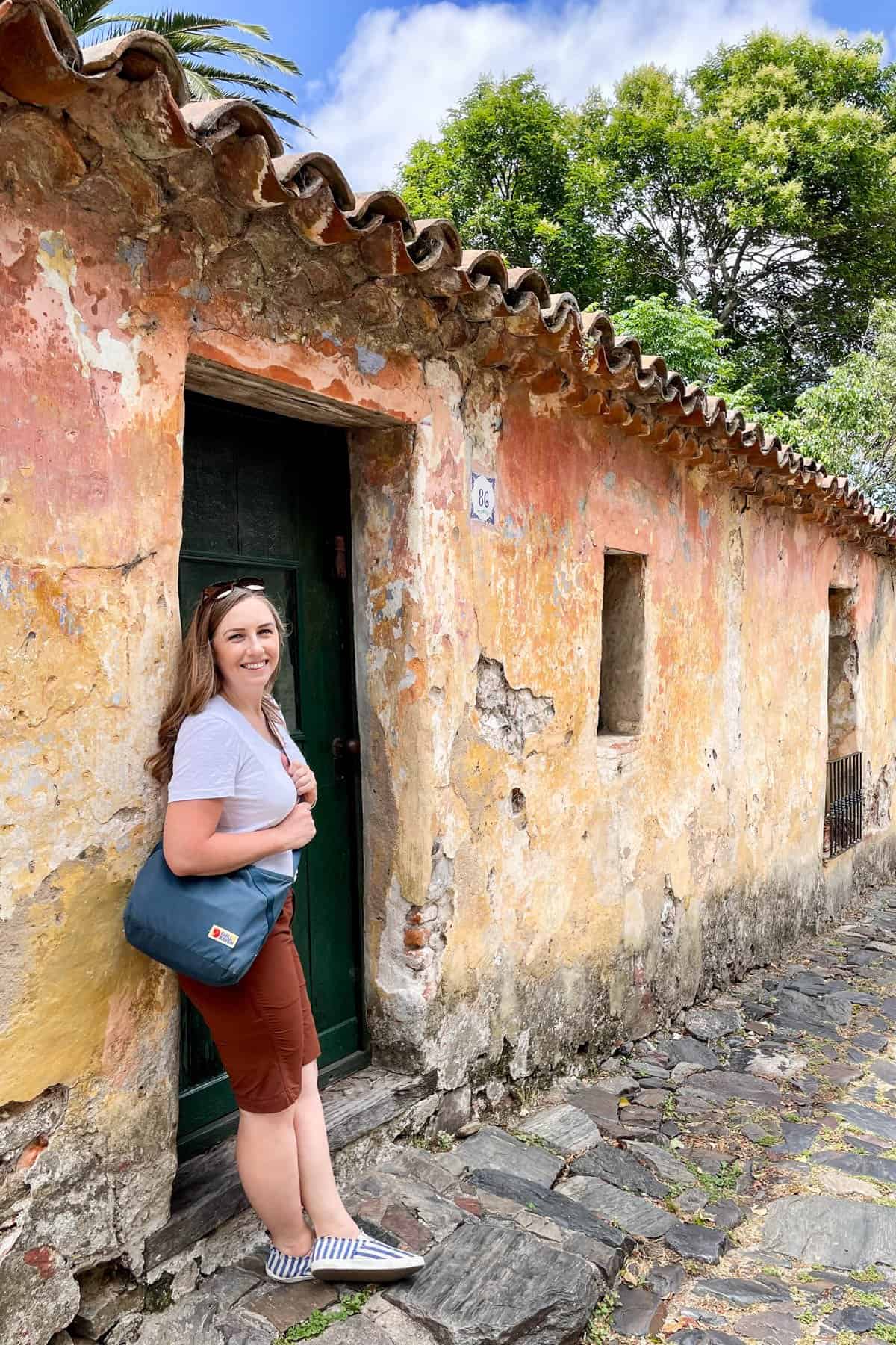 A woman in front of a colorful wall in Colonia, Uruguay.