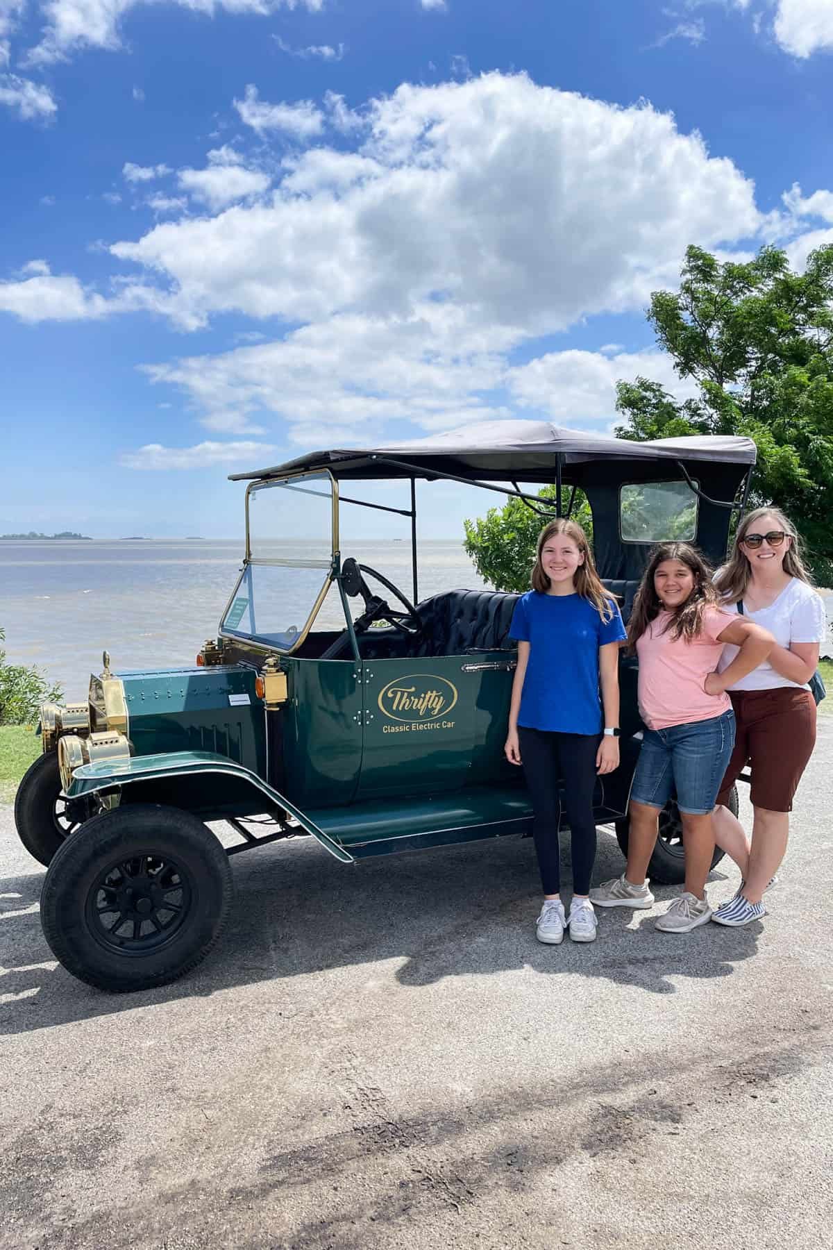 A family standing in front of an old-fashioned car.