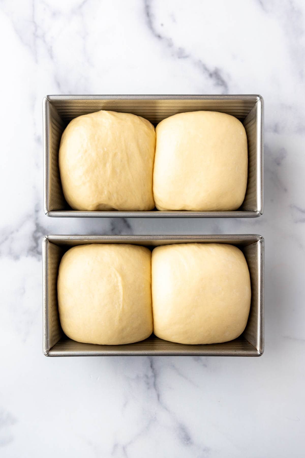 Puffy brioche bread dough in a loaf pan.