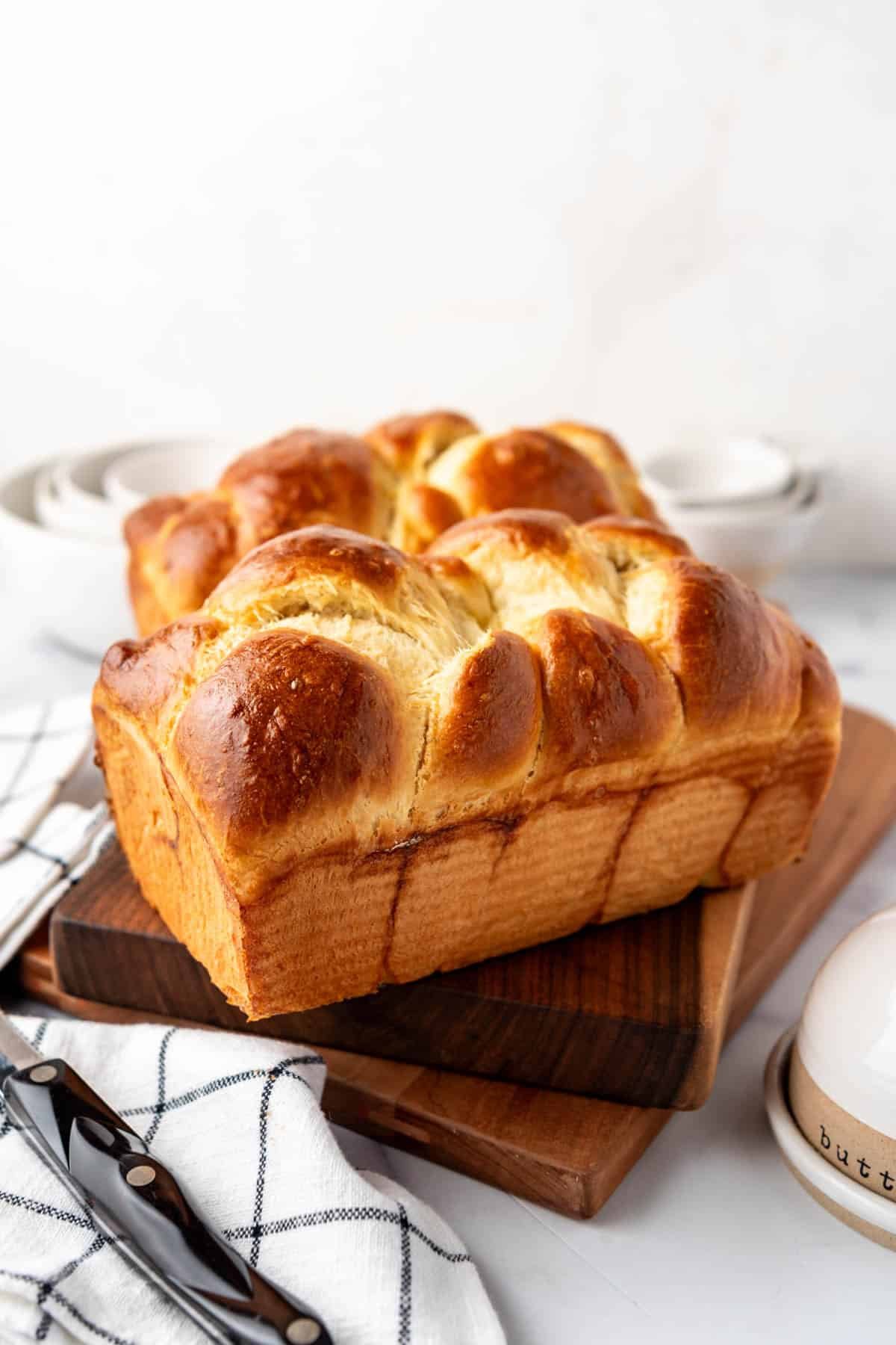 An image of loaves of homemade brioche bread on wooden cutting boards.