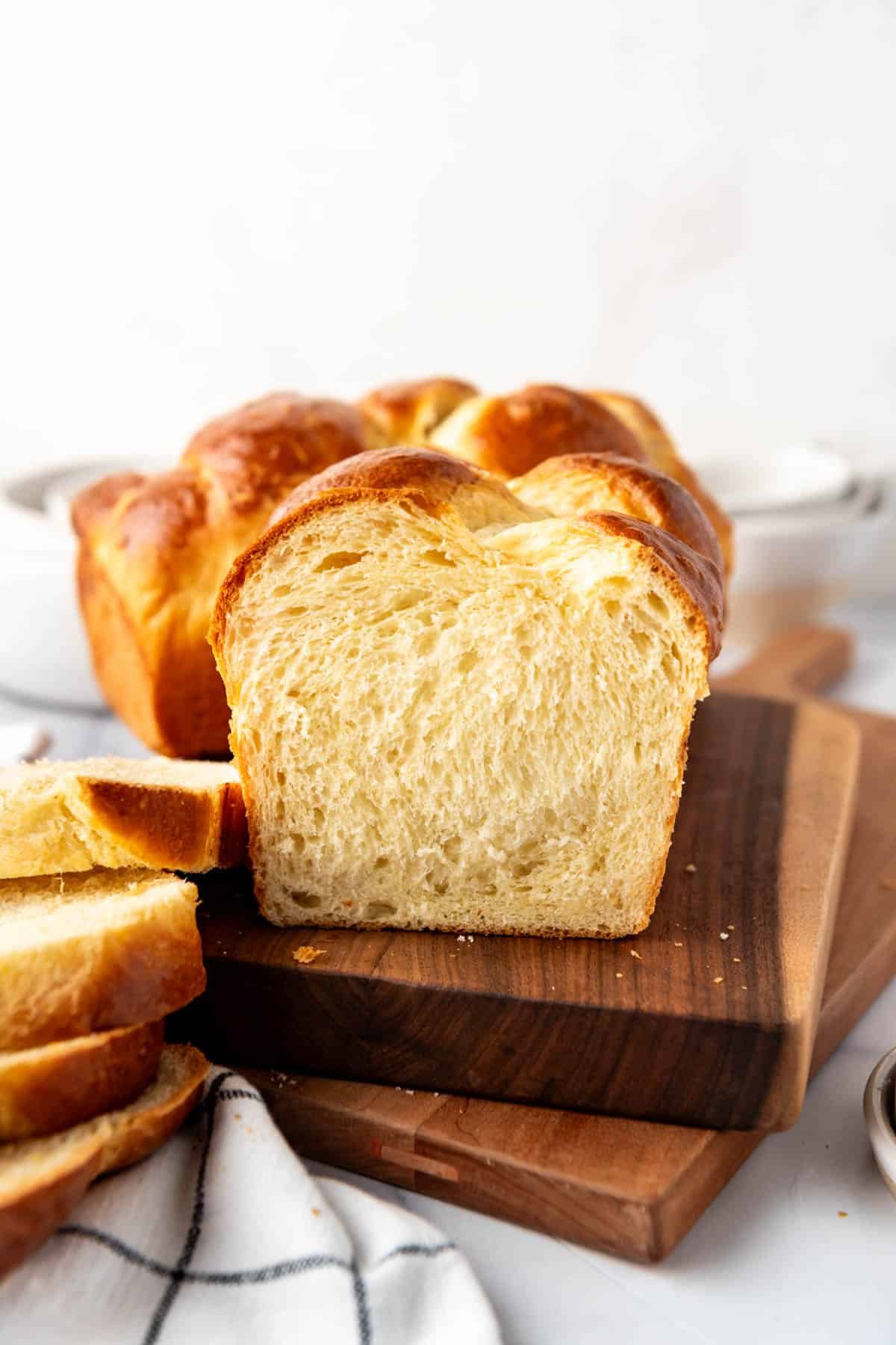 A sliced loaf of brioche bread on a wooden cutting board.