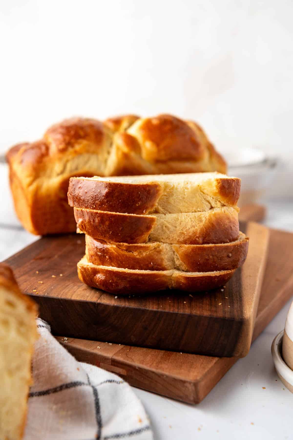 Stacked slices of homemade brioche bread on a wooden cutting board.