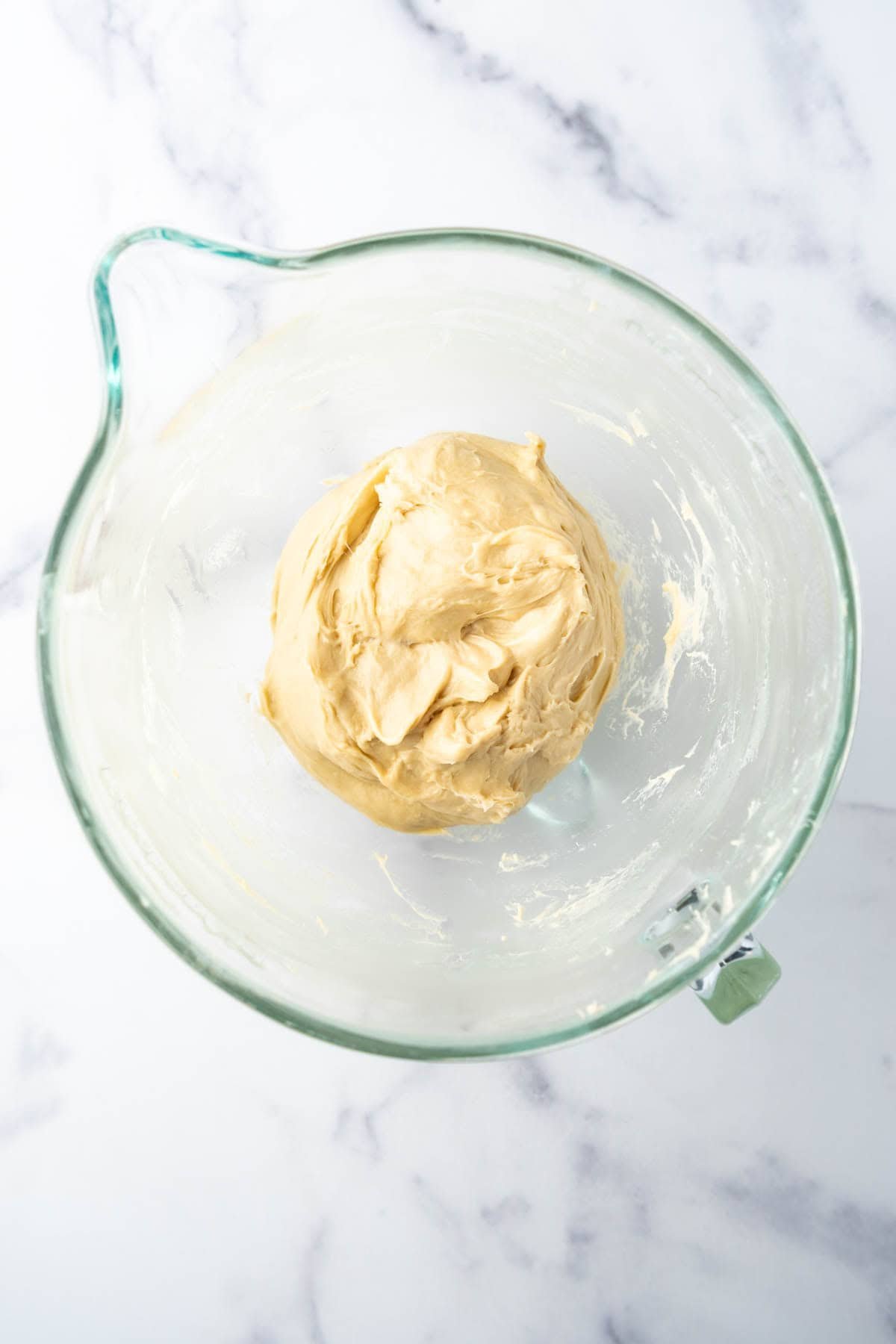 Unrisen brioche bread dough in a glass mixing bowl.