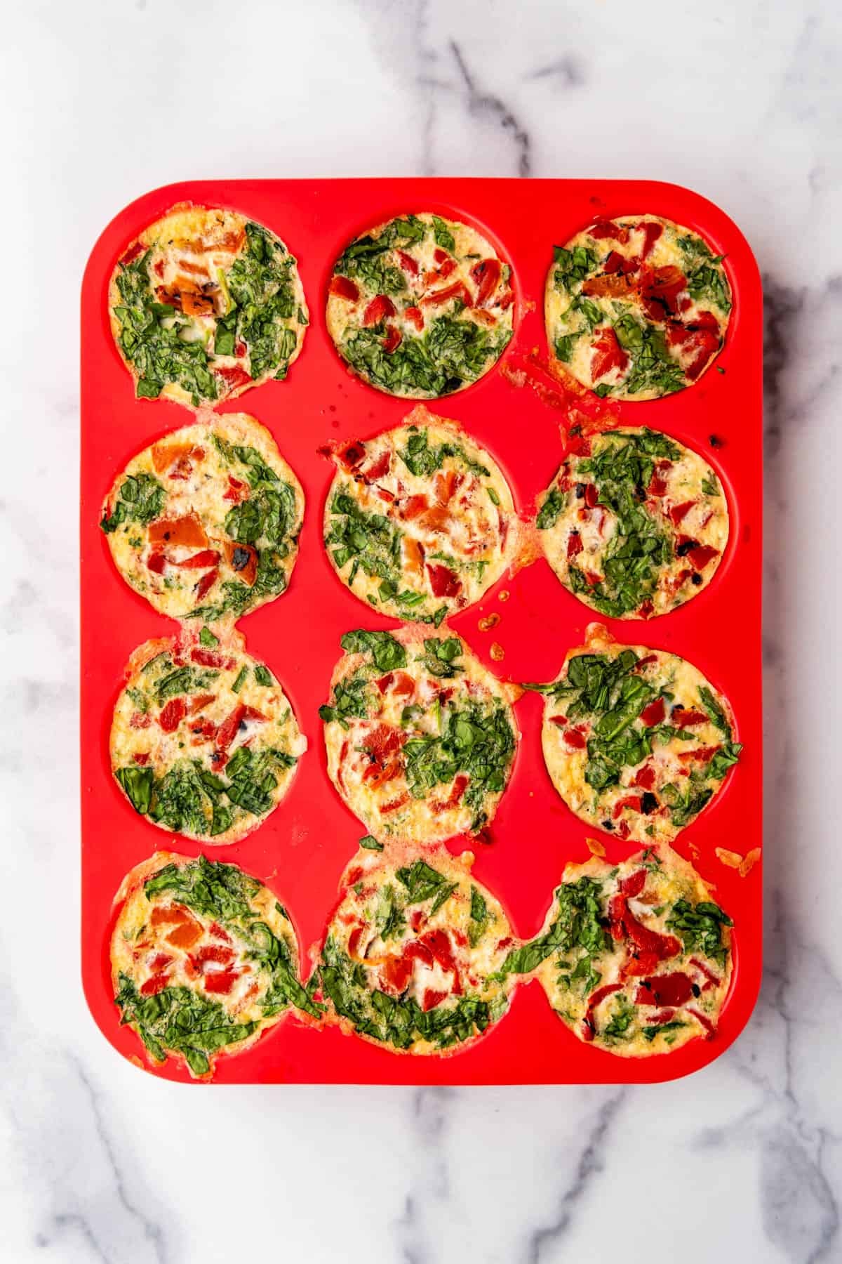 Baked egg white bites in a red silicone muffin pan.